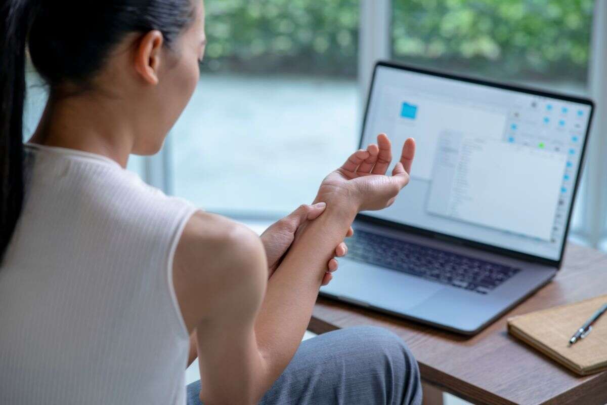 Personne souffrant d'une douleur au poignet lié à l'utilisation de son ordinateur de travail.