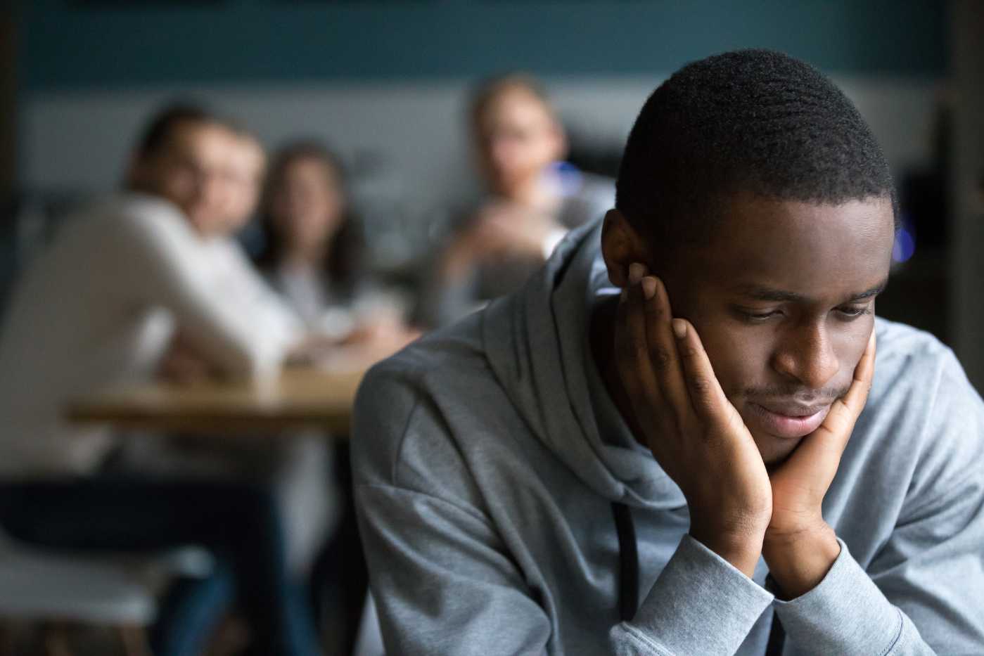 un homme noir se tient la tête dans une classe, d'autres élève le regarde