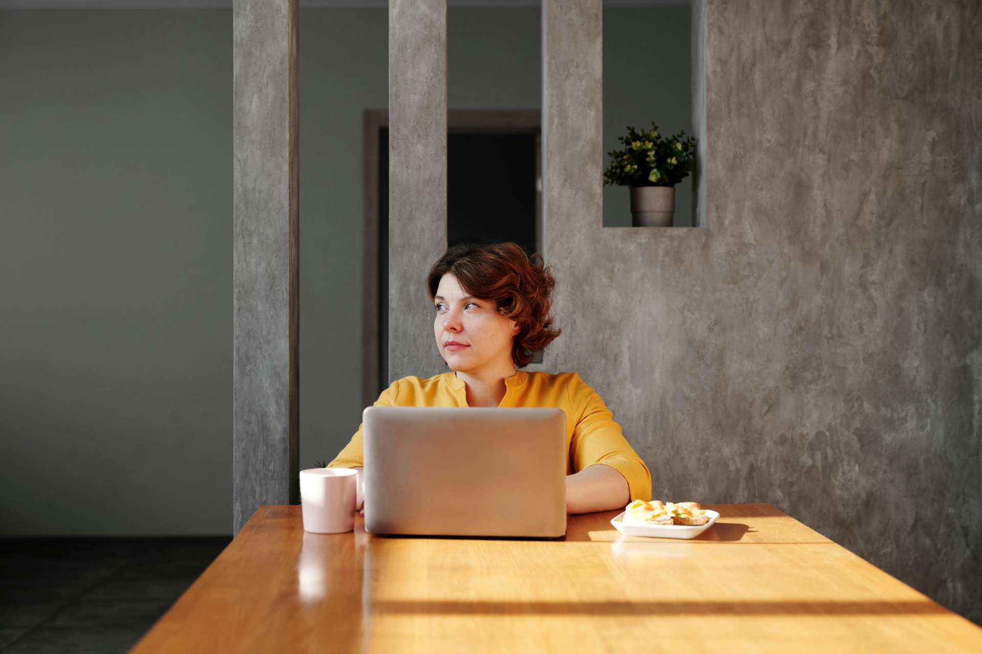une femme est assise à table devant son ordinateur et une tasse de café
